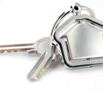 Two silver keys with metal house figure